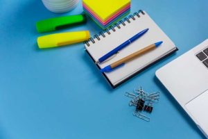Espacio de trabajo organizado con cuaderno, bolígrafos y material de papelería personalizado para oficina